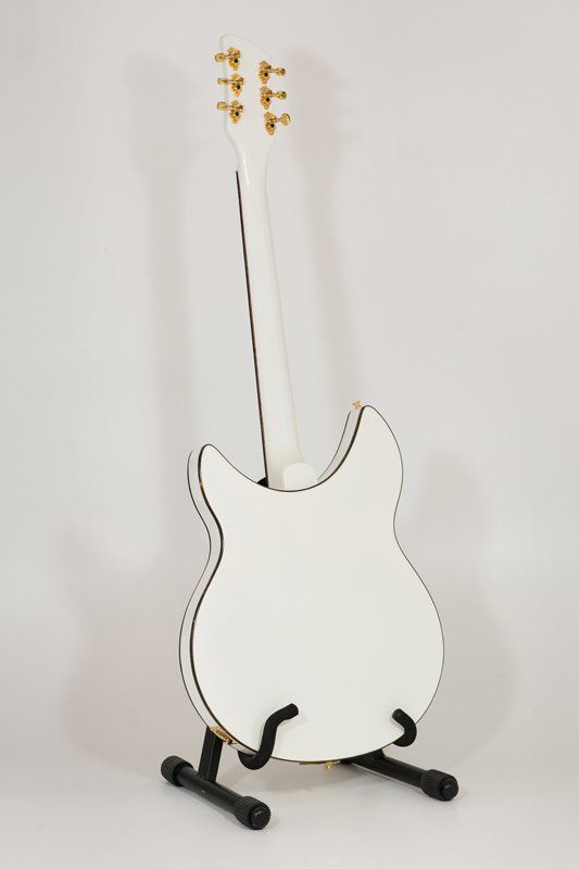 A white electric guitar is sitting on a black stand
