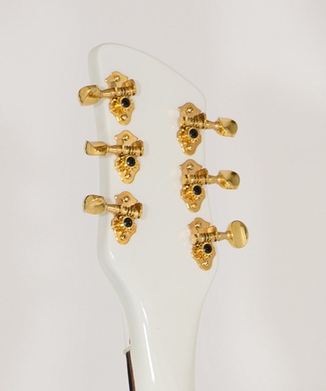 A close up of a white guitar with gold tuners