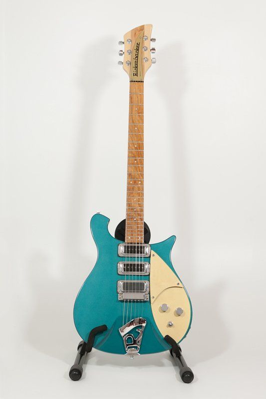 A blue electric guitar is sitting on a stand on a white background.