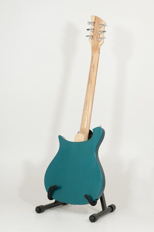 A blue guitar is sitting on a stand on a white background.