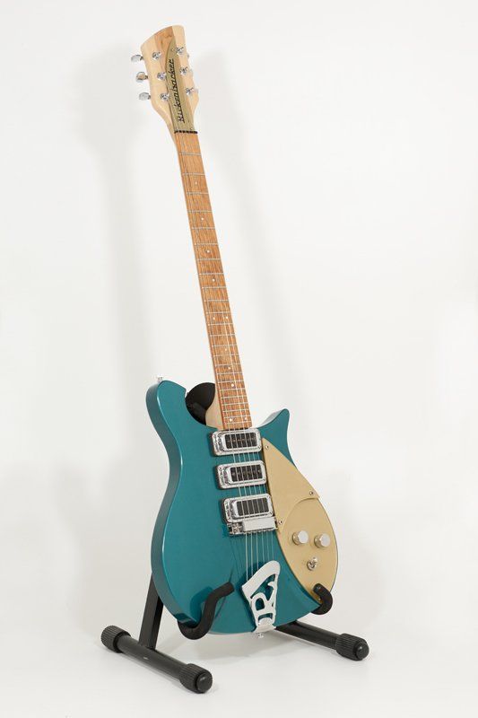 A blue electric guitar is sitting on a stand on a white background.