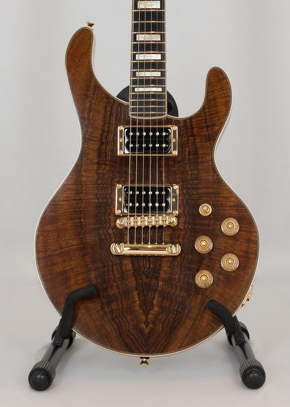 A brown electric guitar is sitting on a stand