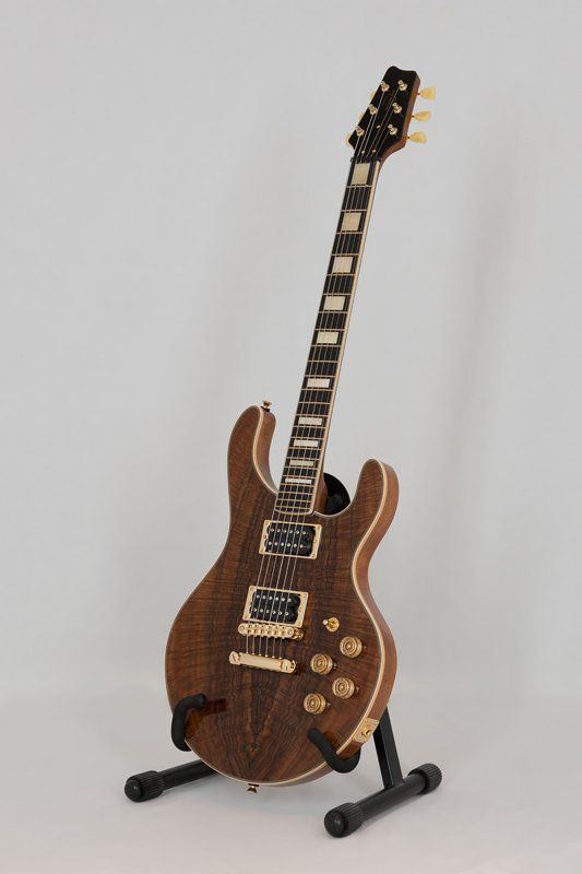 An electric guitar is sitting on a stand on a white surface