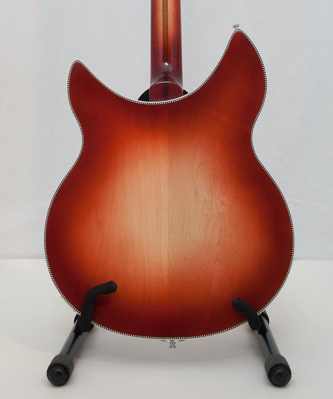 The back of a guitar is shown on a stand