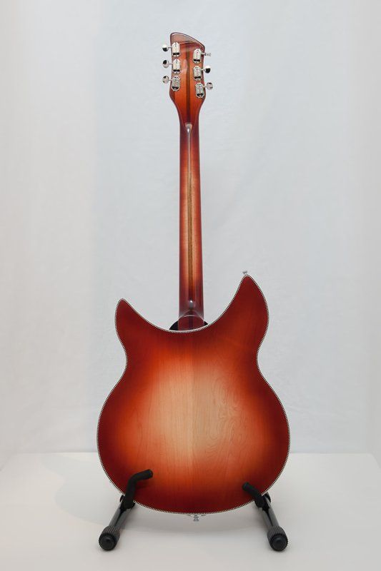 A red electric guitar is sitting on a stand on a white surface.