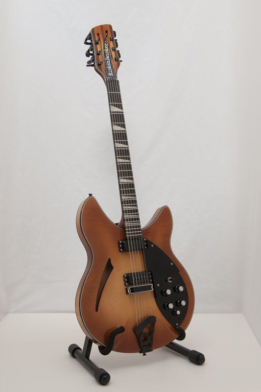 A guitar is sitting on a stand on a table.