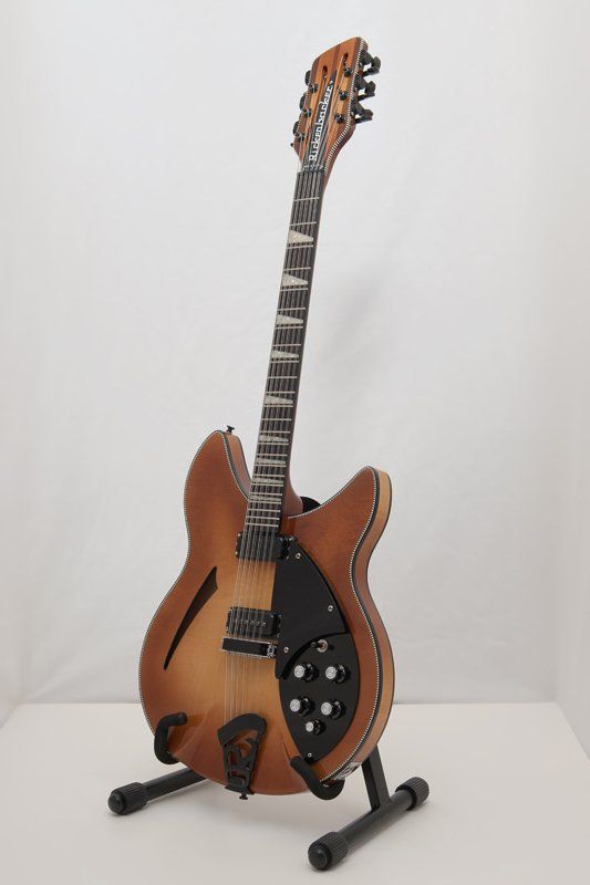 A guitar is sitting on a stand on a table.