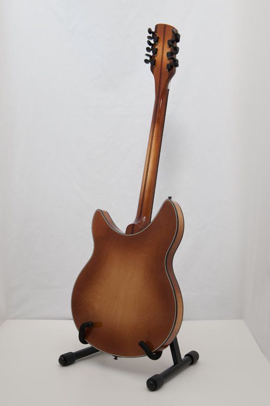 A guitar is sitting on a stand on a table.