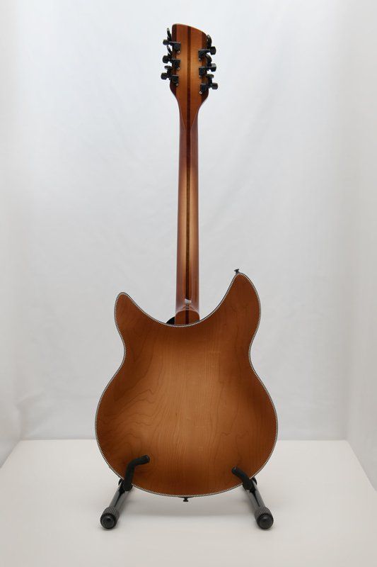 A guitar is sitting on a stand on a white surface.