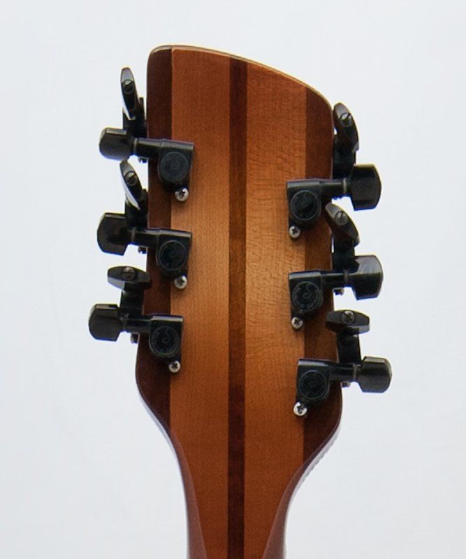 A close up of a guitar headstock with black knobs