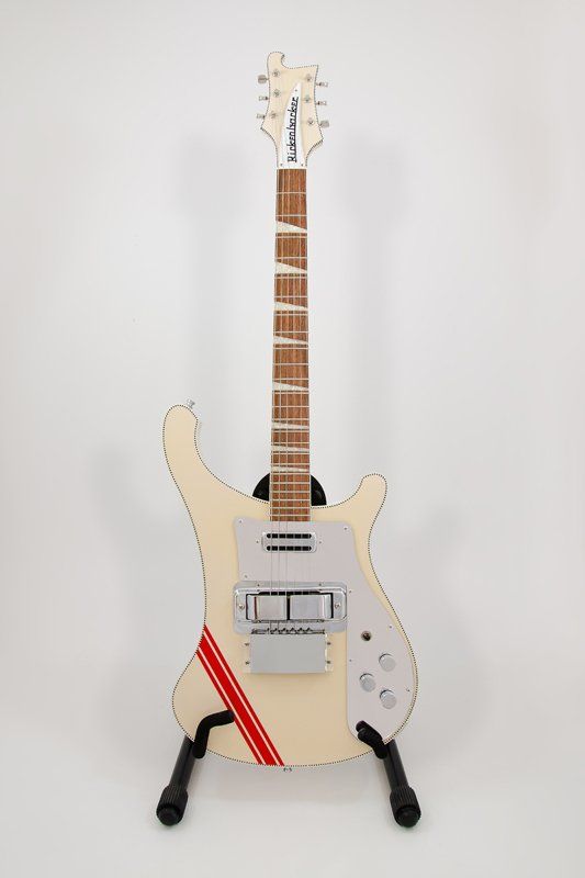 A white electric guitar is sitting on a stand on a white background.