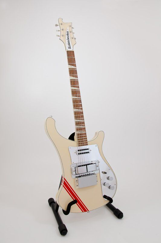 A white electric guitar is sitting on top of a guitar stand.