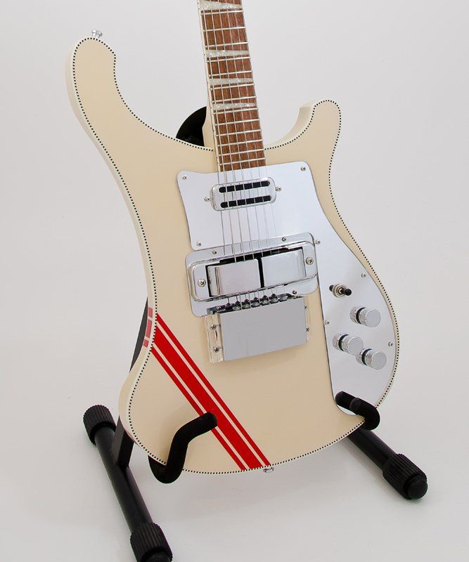 A white guitar with a red stripe on the neck sits on a stand