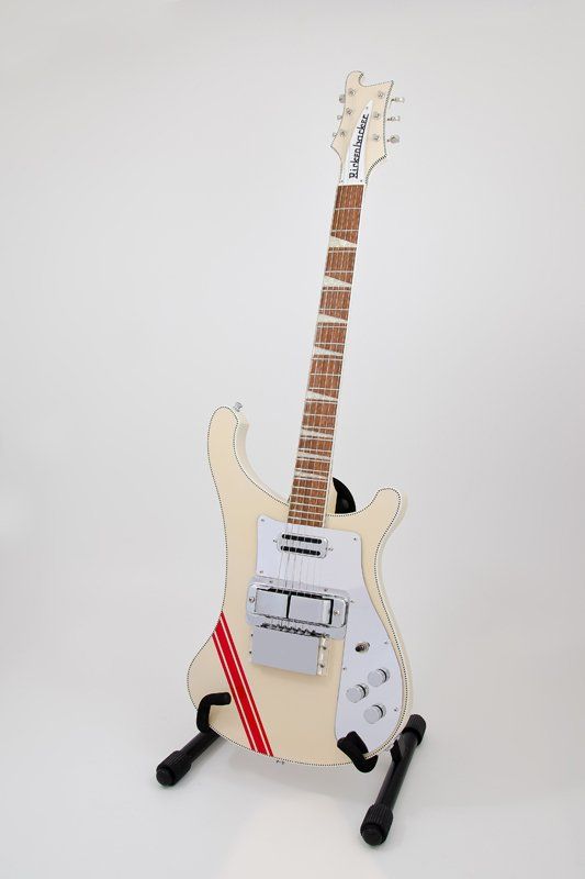 A white electric guitar is sitting on top of a guitar stand.