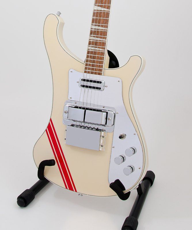 A white electric guitar with a red stripe on the neck sits on a stand