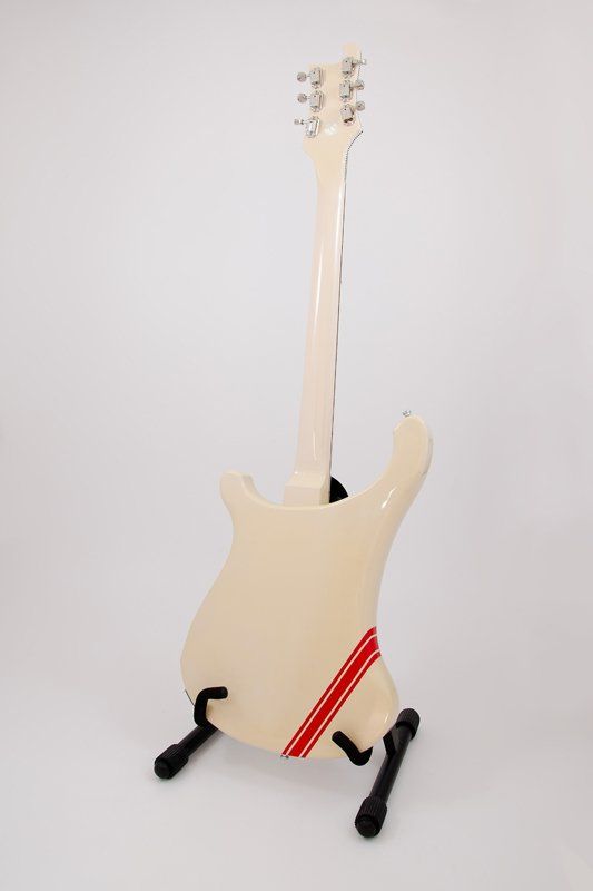 A white electric guitar is sitting on a stand