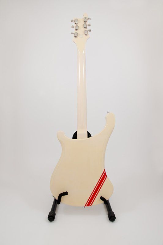 A white electric guitar is sitting on a stand