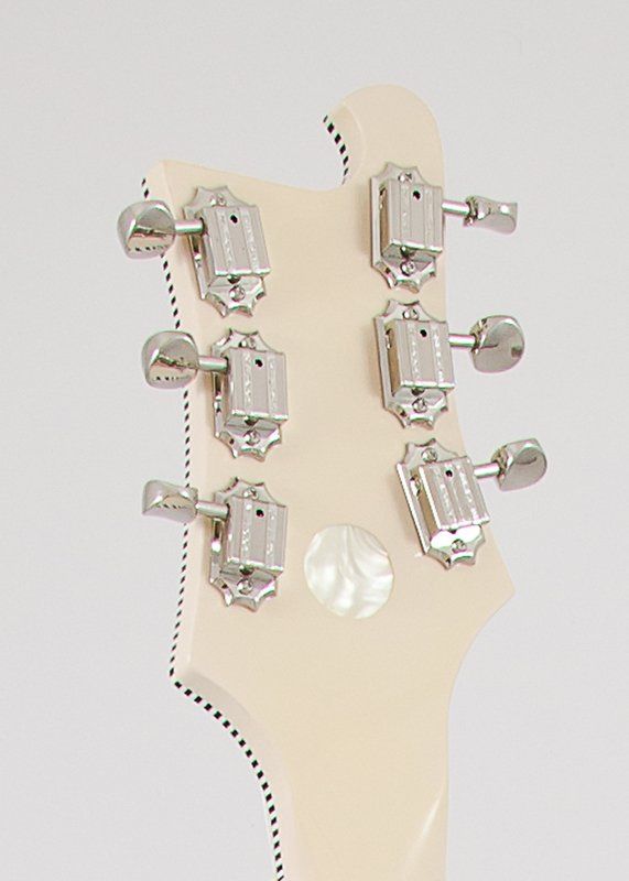 A close up of the headstock of a white electric guitar