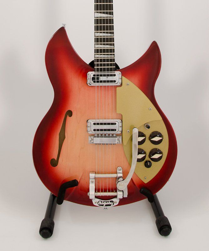 A red and gold guitar is sitting on a stand