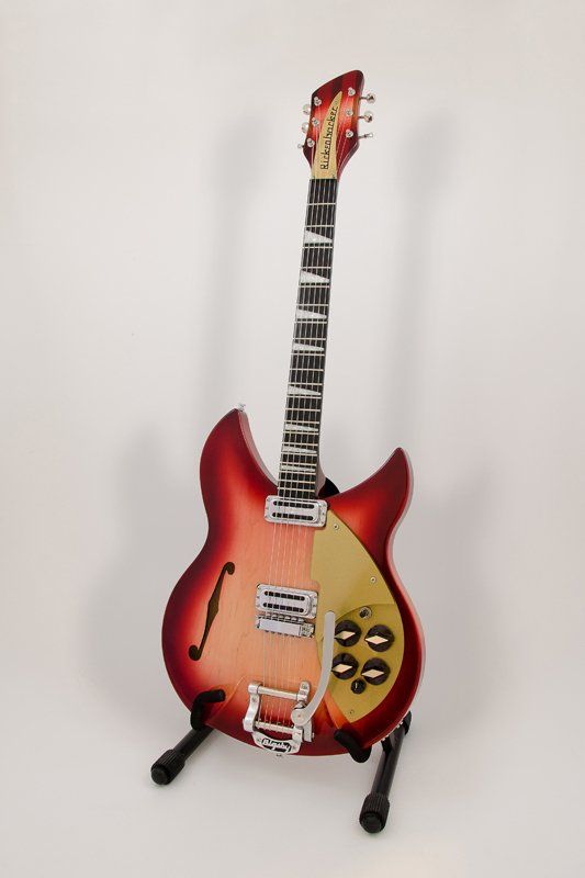 A red and yellow electric guitar is sitting on a stand.