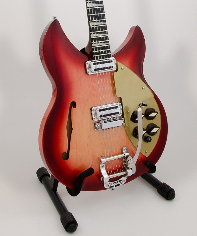 A red guitar is sitting on a black stand