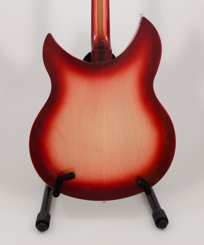 A red guitar is sitting on a stand on a white surface