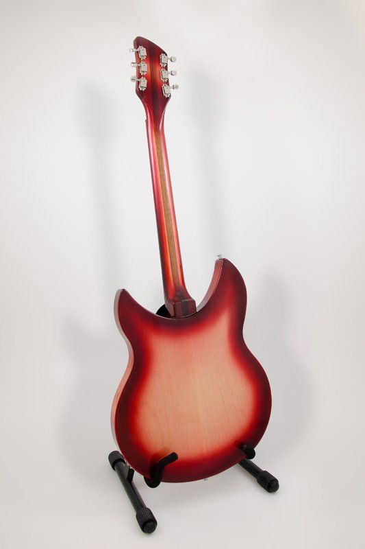 A red electric guitar is sitting on a stand on a white background.