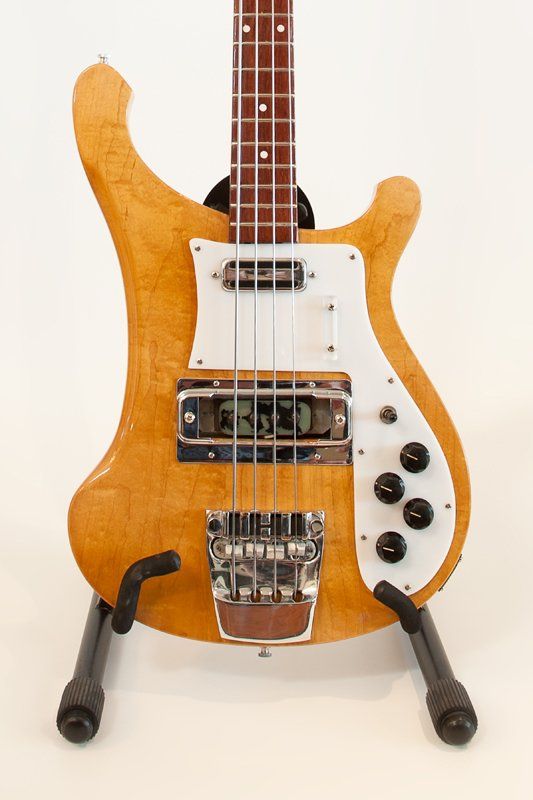 A bass guitar is sitting on a stand on a white background.