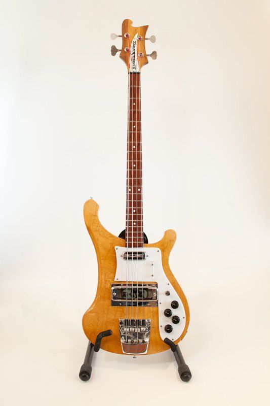 A bass guitar is sitting on a stand on a white background.