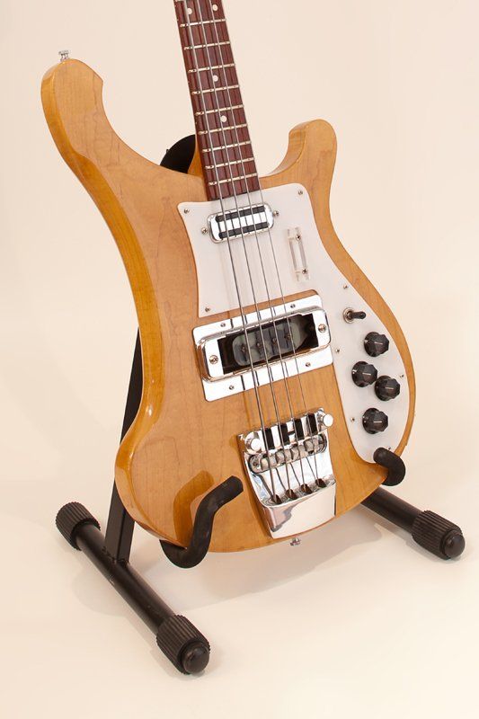 A bass guitar is sitting on a stand on a white background