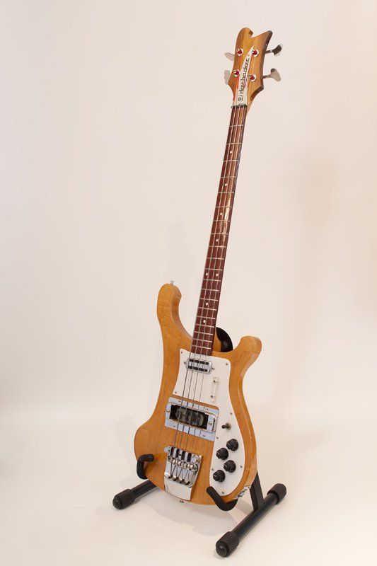 A bass guitar is sitting on a stand on a white background.