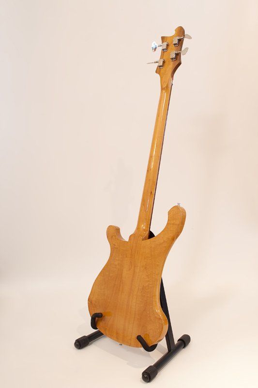A bass guitar is sitting on a stand on a white surface.