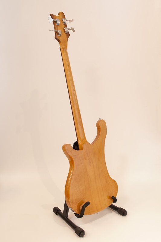 A bass guitar is sitting on a stand on a white surface.