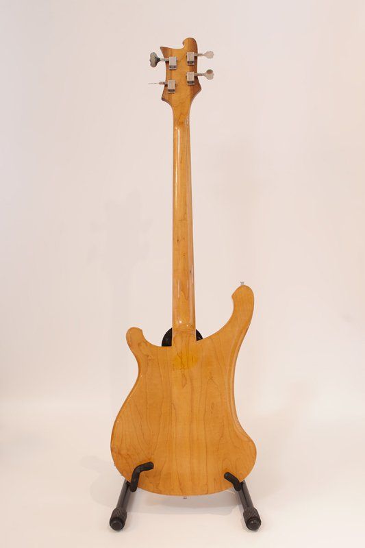 The back of a bass guitar is shown on a stand.