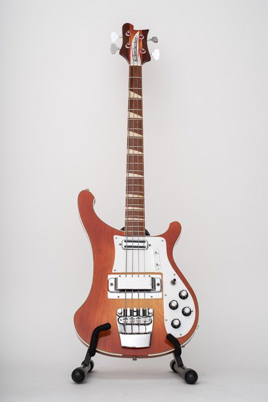 A bass guitar is sitting on a stand on a white background.