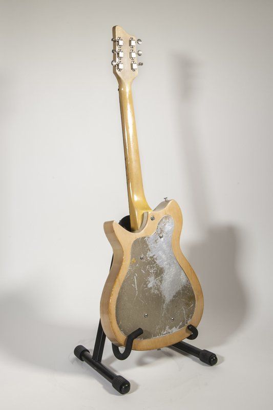 A guitar is sitting on a stand on a white background.