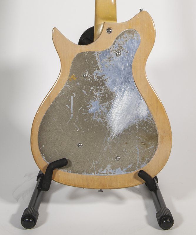 The back of a guitar is shown on a stand