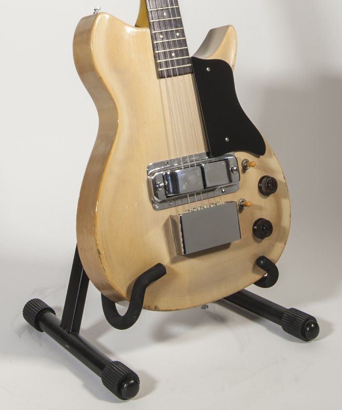 A guitar is sitting on a stand with the letter l on it