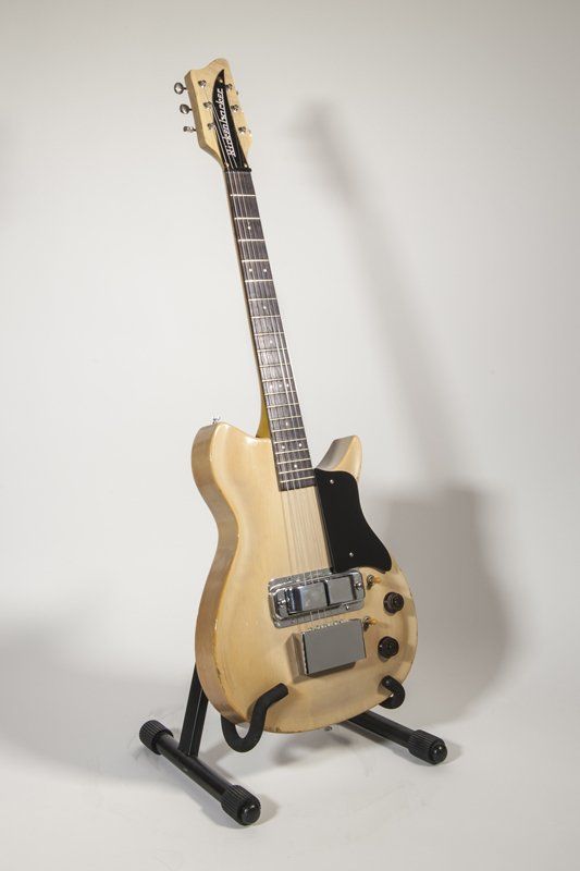 A guitar is sitting on a stand on a white background.