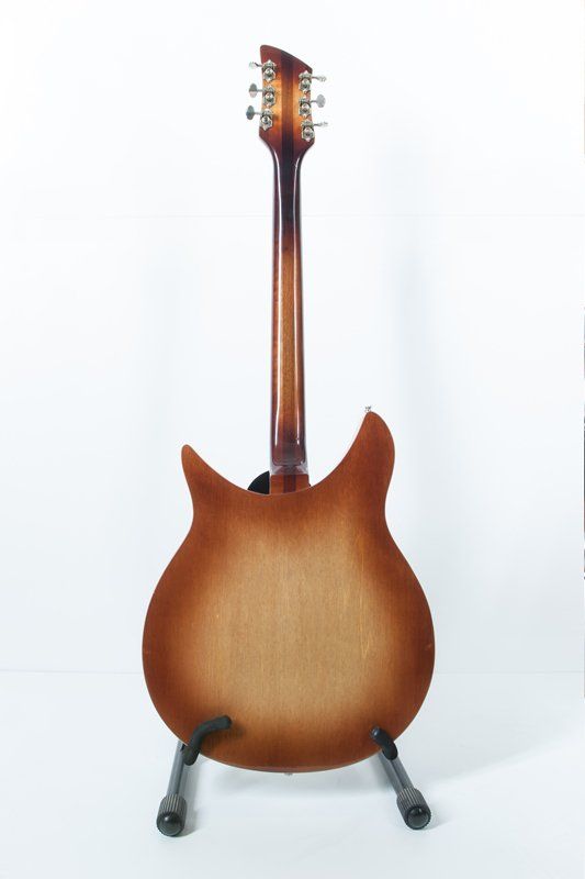 A guitar is sitting on a stand on a white background.