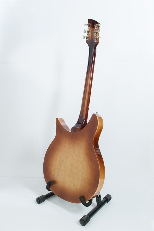 A guitar is sitting on a stand on a white surface.