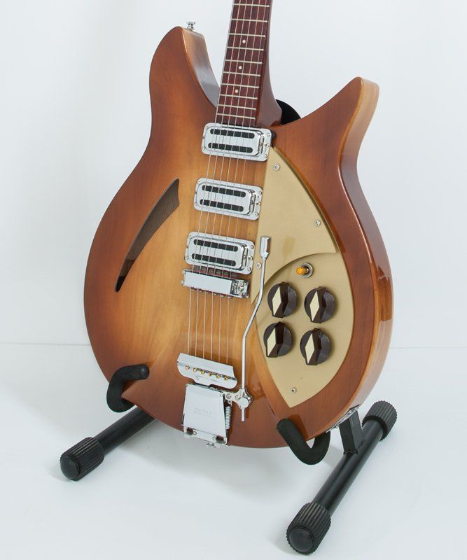 A brown guitar is sitting on a black stand
