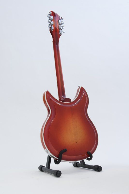 The back of a red electric guitar on a stand