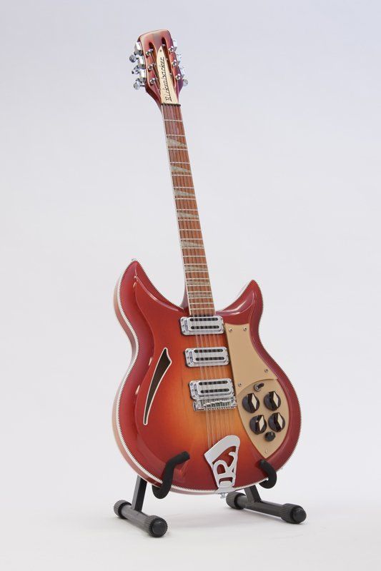 A red electric guitar is sitting on a stand on a white background.