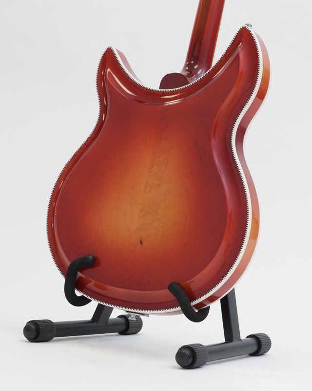 A red guitar is sitting on a black stand