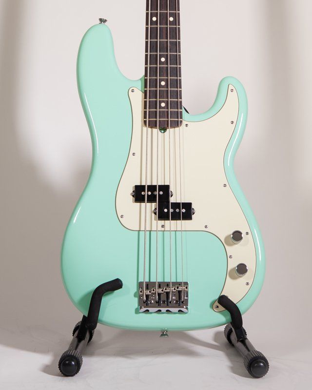 A mint green bass guitar is sitting on a stand