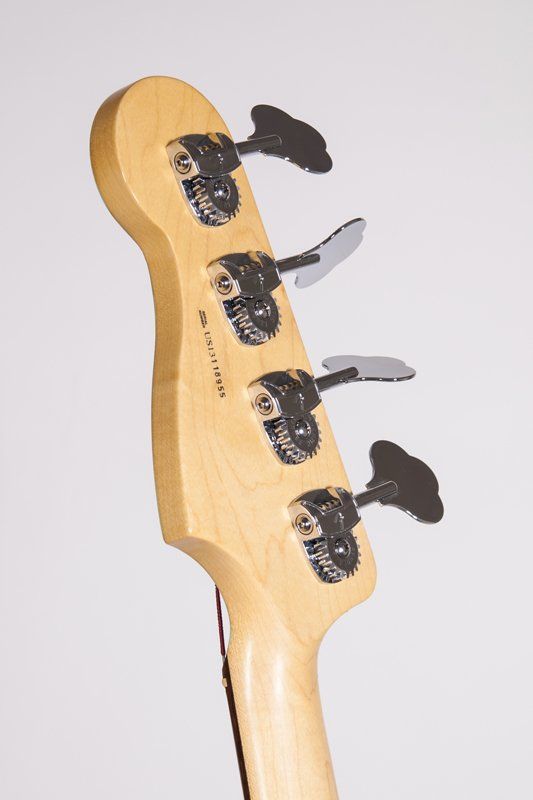 A close up of the headstock of a bass guitar on a white background.