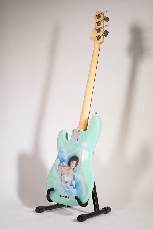 A guitar with a picture of a woman on it is on a stand.