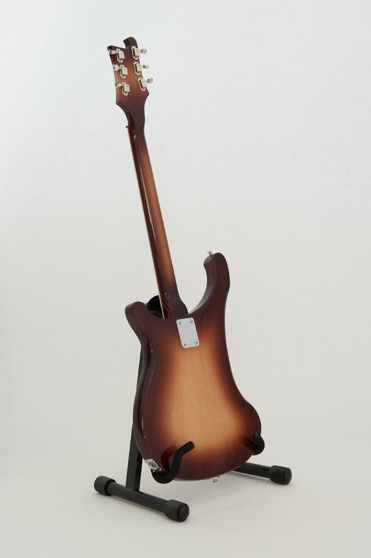 A guitar is sitting on a stand on a white background.