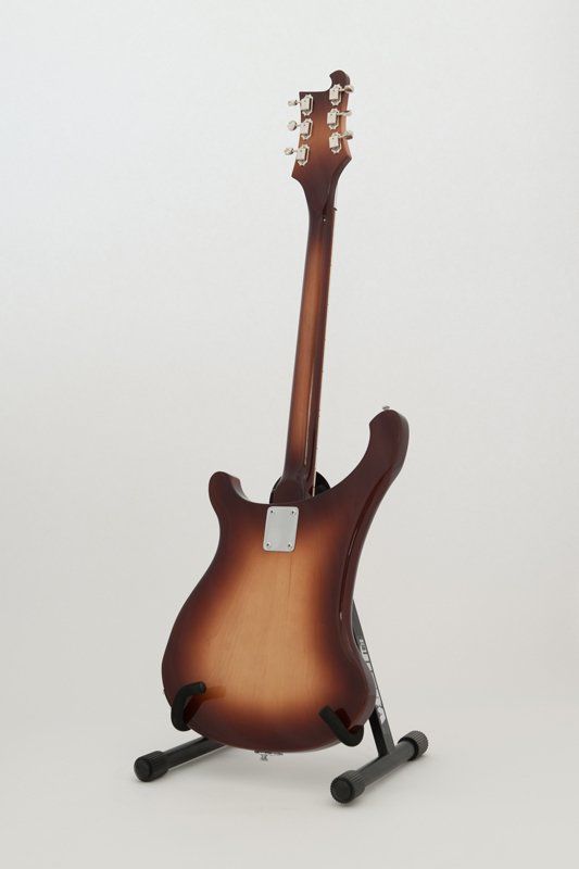 A guitar is sitting on a stand on a white background